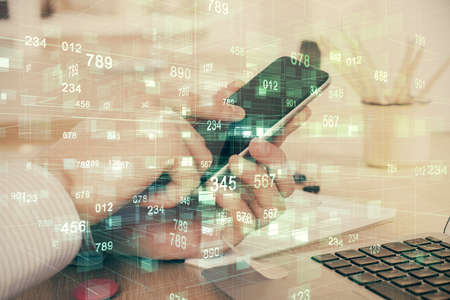 Double exposure of man's hand holding and using a digital device and data theme hologram drawing....