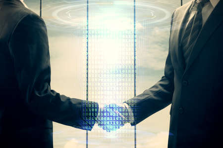 Double exposure of data theme hologram and handshake of two men. Partnership in IT industry concept.