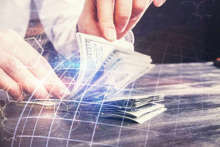 Double exposure of world map drawing hologram and us dollars bills and man hands.の写真素材
