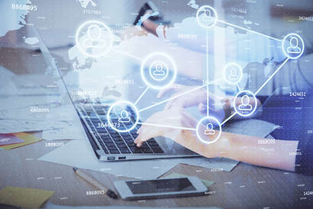 Double exposure of woman hands typing on computer and social network theme hologram drawing. People...