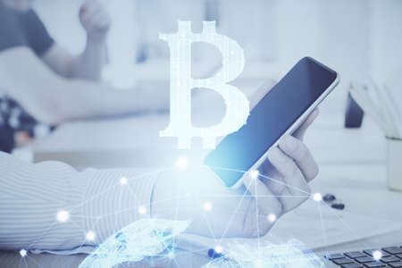 Double exposure of man's hands holding and using a phone and crypto currency blockchain theme drawing.の写真素材