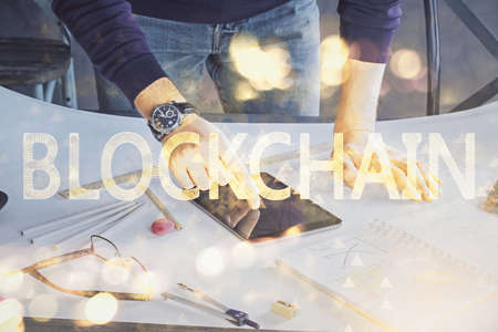 Double exposure of man's hands holding and using a phone and crypto currency blockchain theme drawing.の写真素材