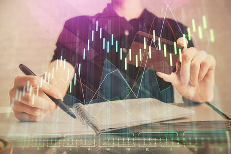Double exposure of man hands holding a credit card and Forex graph drawing. Stock trading and...