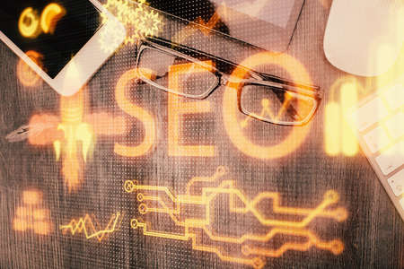 Double exposure of SEO hologram drawing over desktop. Top view. Search optimization concept.の写真素材