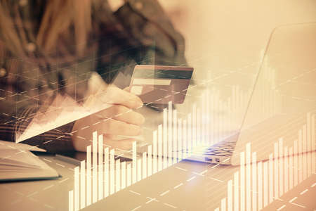 Multi exposure of woman on-line shopping holding a credit card and financial graph drawing. Stock...