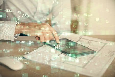 Double exposure of man's hand holding and using a digital device and data theme hologram drawing....