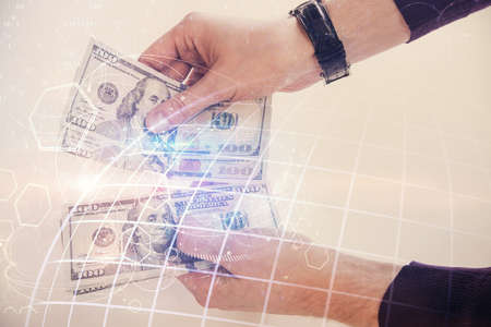 Double exposure of world map drawing hologram and us dollars bills and man hands.の写真素材