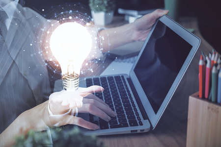 Double exposure of woman hands typing on computer and light bulb drawing. Idea concept.の写真素材