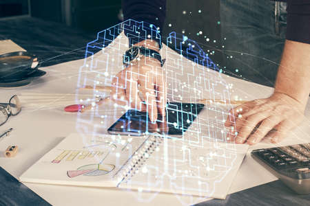 Double exposure of man's hand holding and using a digital device and brain hologram drawing. Data...