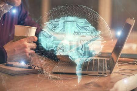 Double exposure of man's hand holding and using a digital device and brain hologram drawing. Data...