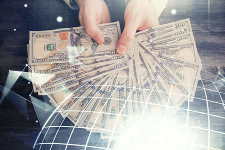Double exposure of world map drawing hologram and us dollars bills and man hands.の写真素材