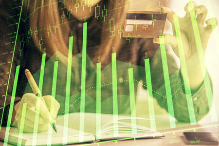 Multi exposure of woman on-line shopping holding a credit card and financial graph drawing. Stock market E-commerce concept.の写真素材