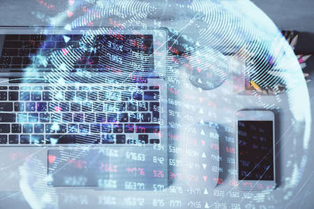 Business theme hologram drawings over computer on the desktop background. Top view. Multi exposure....