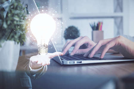 Double exposure of woman hands typing on computer and light bulb drawing. Idea concept.の写真素材