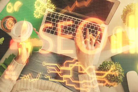 Double exposure of woman hands working on computer and SEO hologram drawing. Top View. Search optimization concept.の写真素材