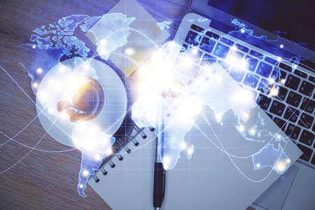 Business theme hologram drawings over computer on the desktop background. Top view. Multi exposure....
