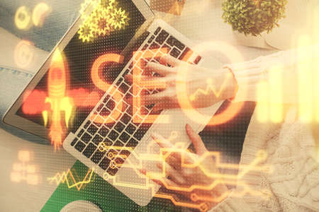 Double exposure of woman hands working on computer and SEO hologram drawing. Top View. Search optimization concept.の写真素材