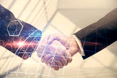 Double exposure of world map hologram and handshake of two men. International partnership concept.
