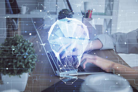 Double exposure of woman hands typing on computer and light bulb drawing. Idea concept.の写真素材