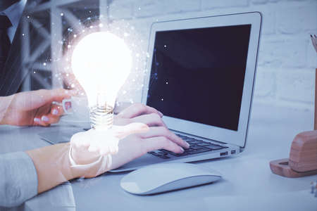 Double exposure of woman hands typing on computer and light bulb drawing. Idea concept.の写真素材