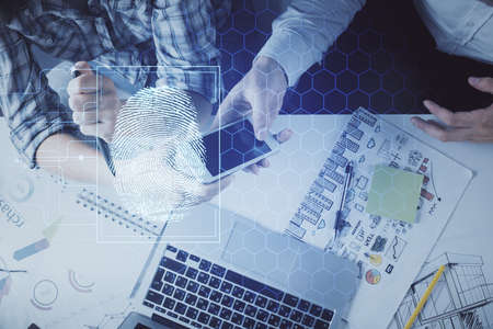 Double exposure of fingerprint hologram and man and woman working together holding and using a...