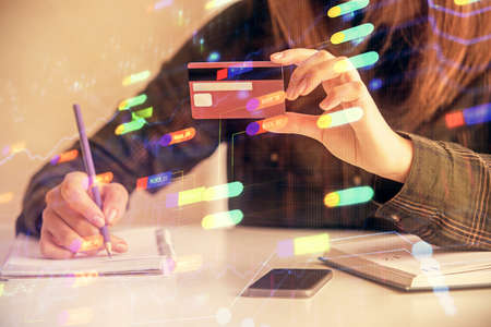 Double exposure of woman on-line shopping holding a credit card and data theme hologram drawing....