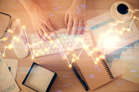 Multi exposure of man's hands typing over computer keyboard and forex graph hologram drawing. Top view. Financial markets concept.の写真素材