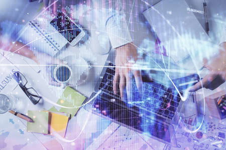 Double exposure of man's hands typing over computer keyboard and business theme hologram drawing....