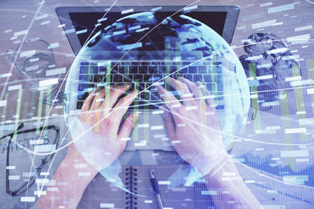 Double exposure of man's hands typing over computer keyboard and business theme hologram drawing....