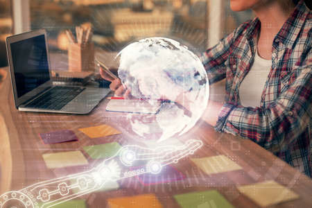 Double exposure of woman hands working on computer and world map hologram drawing. International technology business concept.の写真素材