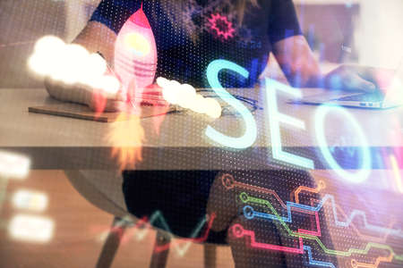 Double exposure of woman hands working on computer and seo hologram drawing. internet search concept.の写真素材
