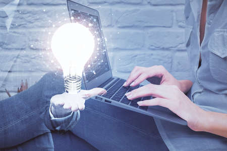 Double exposure of woman hands typing on computer and light bulb drawing. Idea concept.