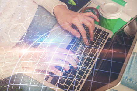 Double exposure of woman hands working on computer and world map hologram drawing. International...
