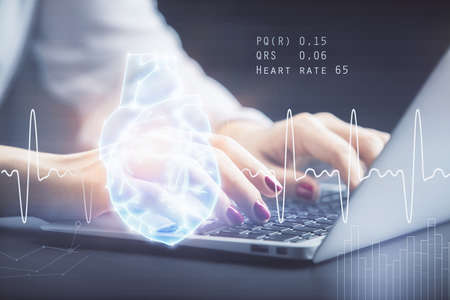 Double exposure of woman hands typing on computer and heart hologram drawing. Education concept.の写真素材