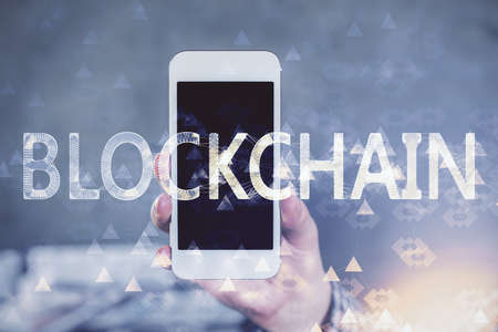 Double exposure of man's hands holding and using a phone and crypto currency blockchain theme...