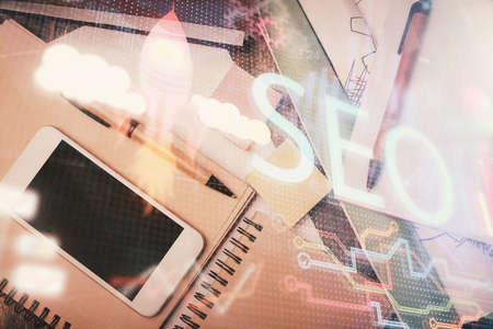 Double exposure of SEO hologram drawing over desktop. Top view. Search optimization concept.