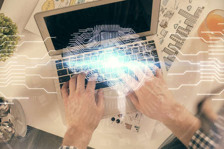 Double exposure of man's hands typing over computer keyboard and brain hologram drawing. Top view....