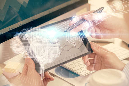 Double exposure of man's hand holding and using a digital device and brain hologram drawing. Data...