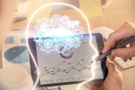 Double exposure of man's hand holding and using a digital device and brain hologram drawing. Data...