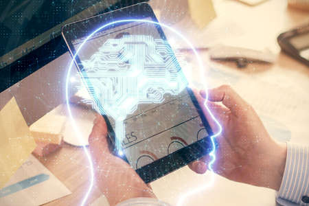 Double exposure of man's hand holding and using a digital device and brain hologram drawing. Data...
