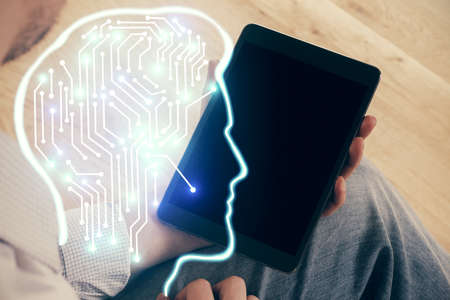 Double exposure of man's hand holding and using a digital device and brain hologram drawing. Data...