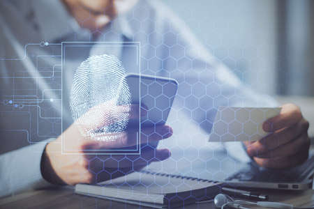 Double exposure of man's hands holding and using a digital device and fingerprint hologram drawing....