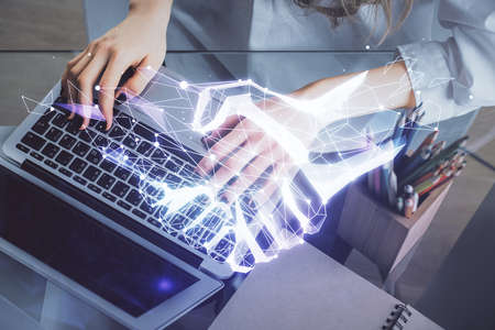 Double exposure of woman hands typing on computer and handshake drawing. Partnership concept.の写真素材