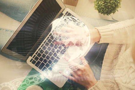 Double exposure of woman hands working on computer and world map hologram drawing. Top View. International business concept.の写真素材