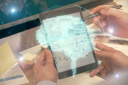 Double exposure of man's hand holding and using a digital device and brain hologram drawing. Data...