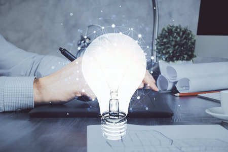 Double exposure of man's hands holding and using a digital device and bulb hologram drawing. Idea concept.の写真素材