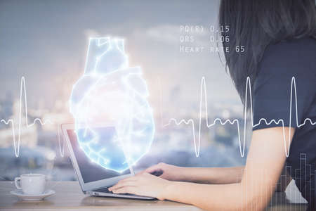 Double exposure of woman hands typing on computer and heart hologram drawing. Education concept.の写真素材