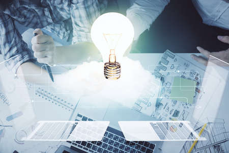Double exposure of bulb hologram and man and woman working together holding and using a mobile...