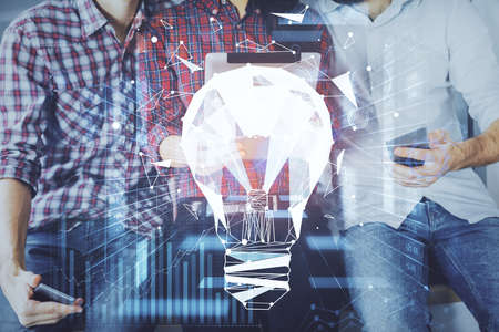 Double exposure of bulb hologram and man and woman working together holding and using a mobile device. Idea conceptの写真素材