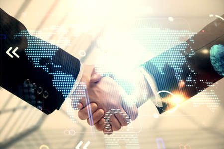 Double exposure of world map hologram and handshake of two men. International partnership concept.